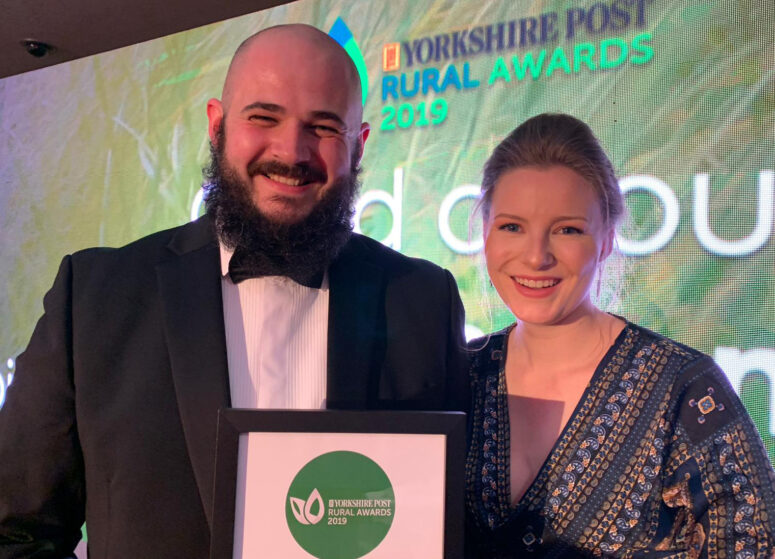 A man and a woman at an awards ceremony holding a special recognition award